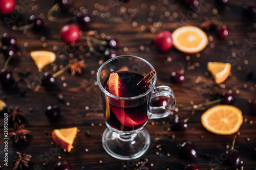 Mulled wine with spices and fruits on wooden background