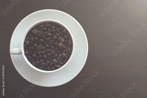 White mug with coffee beans. Wooden table. Toned photo. Copy space