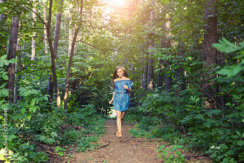 Nature, people and lifestyle concept - Beautiful young woman in dress runing in the summer forest