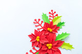 Paper flower poinsettia and leaves of holly