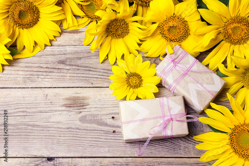 Fototapeta Naklejka Na Ścianę i Meble -  Background with yellow sunflowers and gift boxes on wooden table.