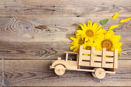 Fototapeta Naklejka Na Ścianę i Meble -  Wooden toy truck with yellow sunflowers in the back on rustic background. Space for text.