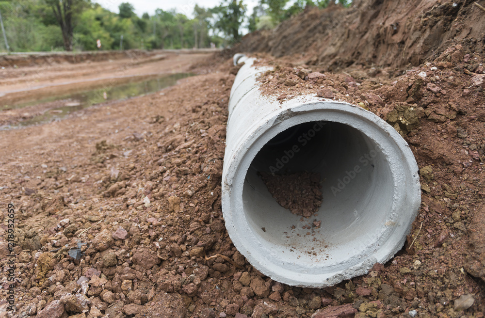 Concrete Drainage Pipe row on a Construction Site near ditch. Concrete pipe stacked sewage water system aligned on site. Concrete Drainage Pipe row on a Construction Site near ditch. Concrete pipe stacked sewage water system aligned on site.