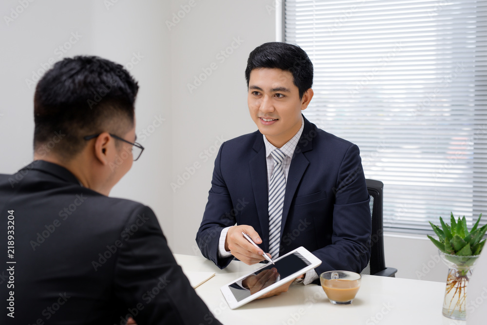 Business meeting. Two business people sitting in front of each other in the office while discussing something Business meeting. Two business people sitting in front of each other in the office while discussing something