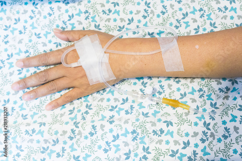 Focus on the hands of female patients take saline intravenous in the hospital.- Health care concept