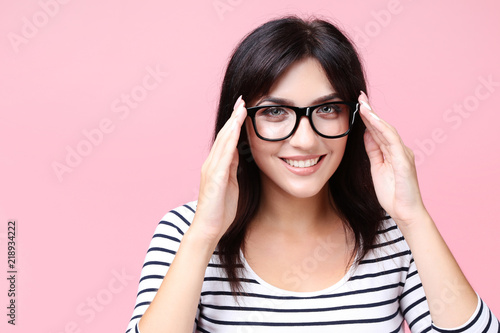 Young woman with glasses on pink background