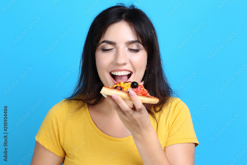 Young woman eating pizza on blue background Young woman eating pizza on blue background
