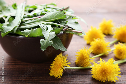 Fototapeta Naklejka Na Ścianę i Meble -  Yellow dandelions with green leafs on wooden table
