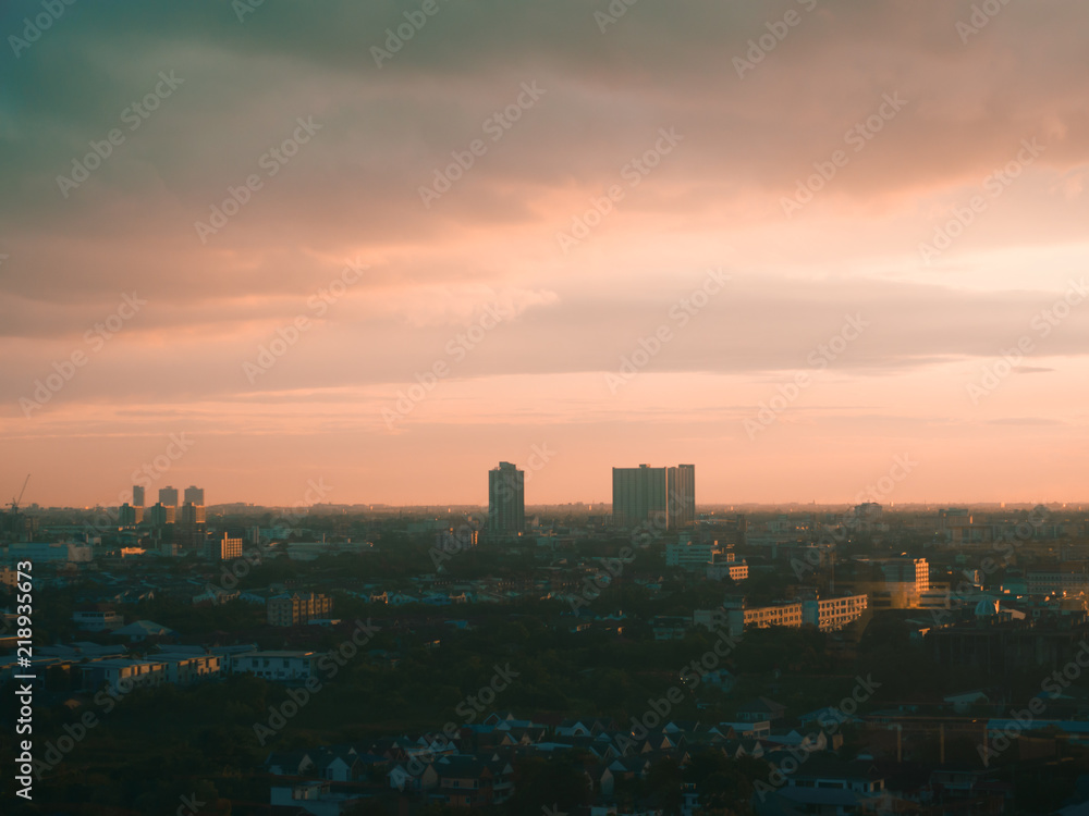 Cityscape of unknow city with thick clouds and sunset light.