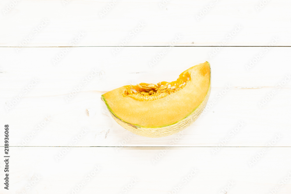 One slice of fresh melon cantaloupe variety flatlay on grey wood