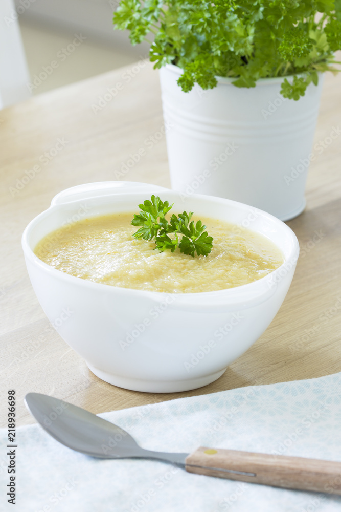 Creamy cauliflower soup with parsley on kitchen table Creamy cauliflower soup with parsley on kitchen table