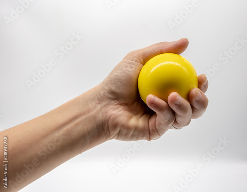 Hand holding yellow stress ball isolated on white