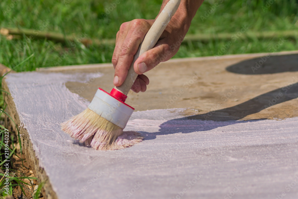 Fotografie Workers hand  holding a brush and puts primer on concrete floor