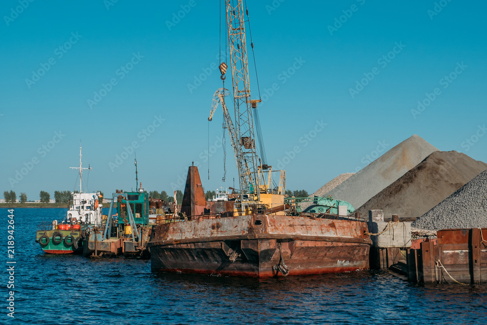 Industrial cargo port with old ships on river, water logistics