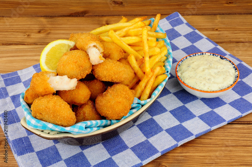 Scampi and French fries meal with tartar sauce on a wooden background