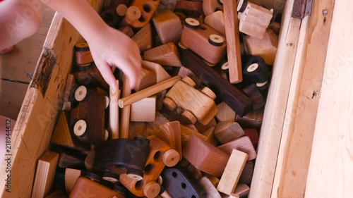 Child pulls wooden toys from a wooden box. Close-up hands. photo