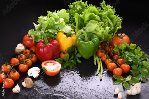Vegetables and fruits with water drops on black granite table