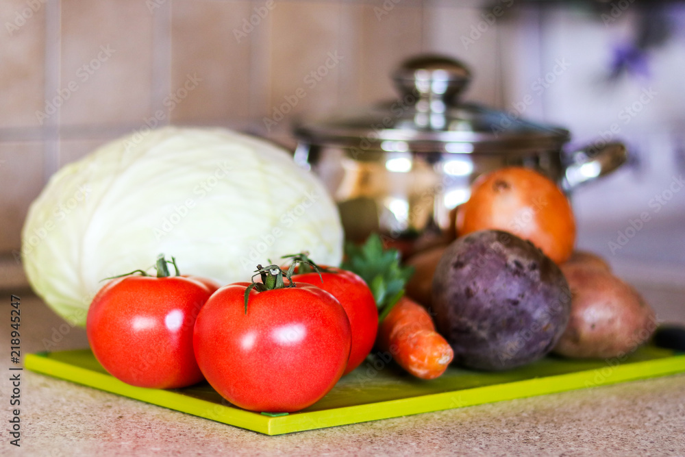 Ingredients for ukrainian traditional borsh on the green cutting desk with cooking pot at background. Selective focus. Ingredients for ukrainian traditional borsh on the green cutting desk with cooking pot at background. Selective focus.
