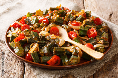 Serve Organic okra with tomatoes and onion close-up on a plate on the table. horizontal, rustic style