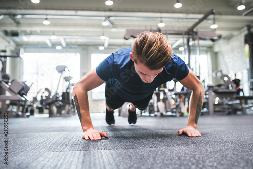 Young fit man in gym doing push ups.