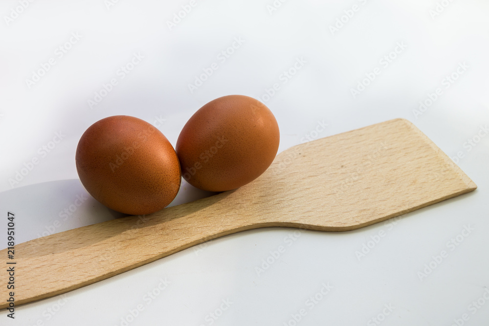 Two chicken eggs and a wooden spatula. Omelette. Cooking an omelet. Raw eggs. Two chicken eggs and a wooden spatula. Omelette. Cooking an omelet. Raw eggs.