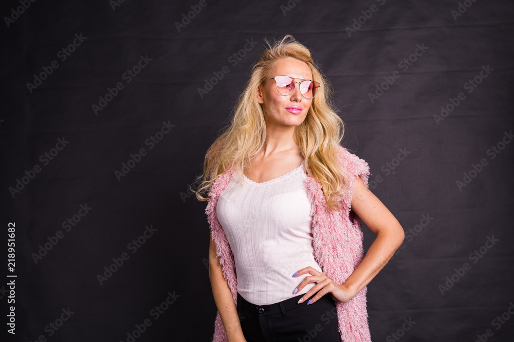 Fashion and beauty concept - portrait of blond model dressed in white shirt and pink cardigan over black background with copy space Fashion and beauty concept - portrait of blond model dressed in white shirt and pink cardigan over black background with copy space
