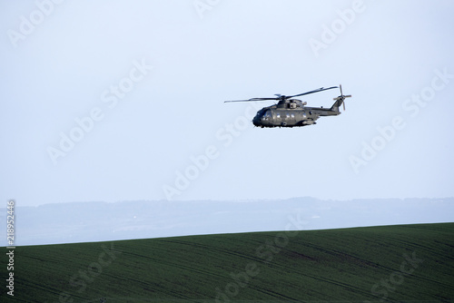 A helicopter flying over farmland in Devon England UK