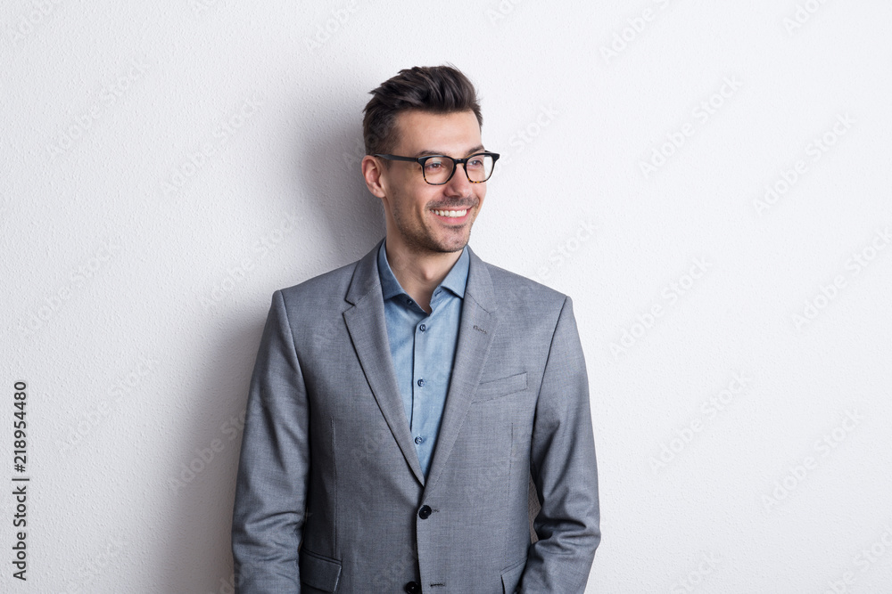 Portrait of a cheerful young man with glasses in a studio. - obrazy, fototapety, plakaty 