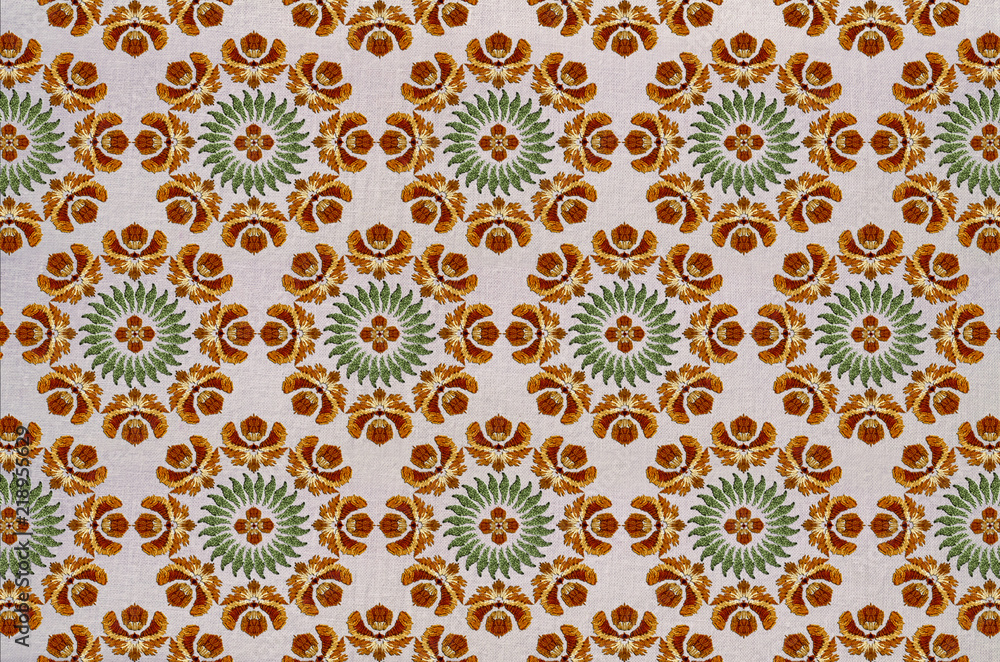 Seamless cotton fabric of round embroidery with stylized orange flowers, wreath of green leaves and a flower in the center

