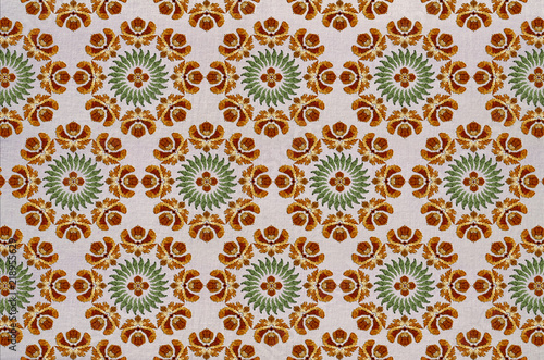 Seamless cotton fabric of round embroidery with stylized orange flowers, wreath of green leaves and a flower in the center