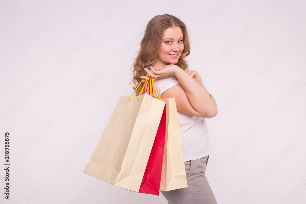 People, sale and consumerism concept - Beautiful woman over white background holding shopping bags