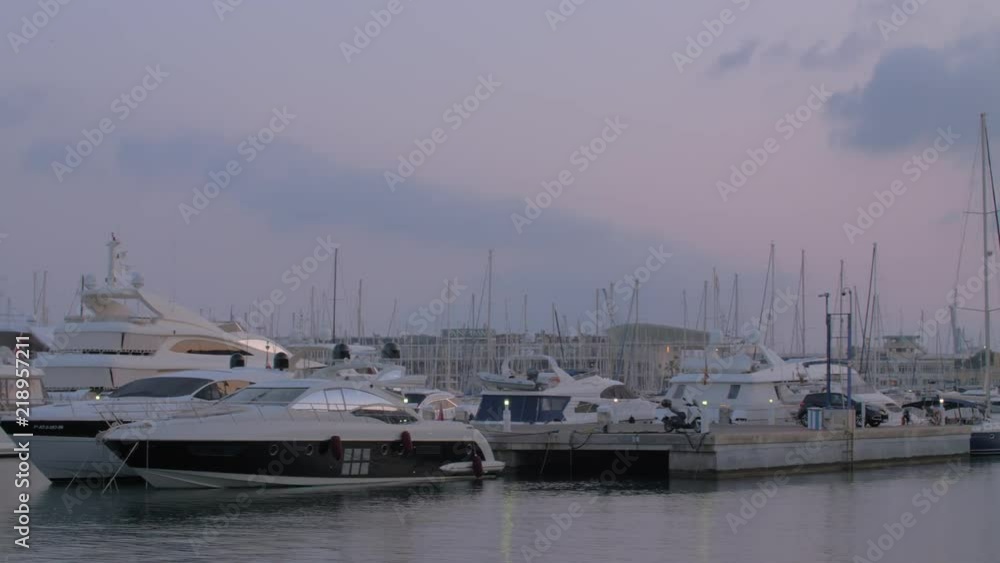 Panning shot of harbour with many yachts at anchor. Evening water scene