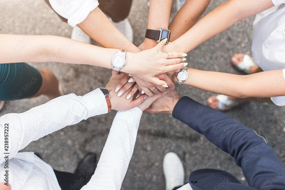 business, people and teamwork concept - smiling group of businesspeople standing in circle and putting hands on top of each other