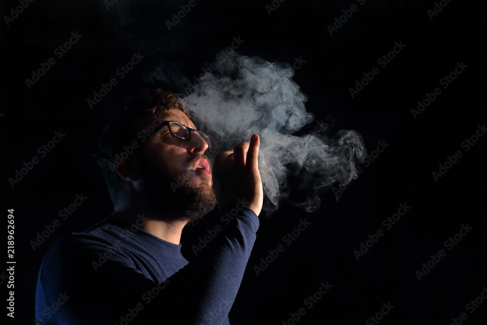 man brunette with a cigarette in the dark, a lot of smoke man brunette with a cigarette in the dark, a lot of smoke