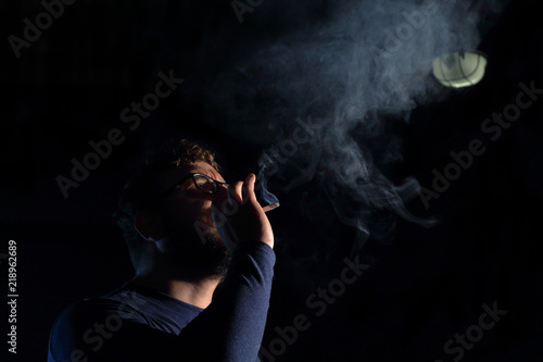 man brunette with a cigarette in the dark, a lot of smoke