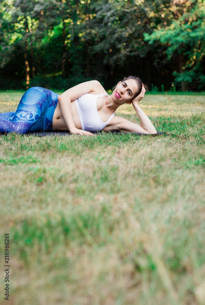 Slim young woman lying on green grass. Sport concept