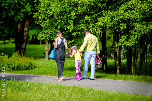 Parents teach their daughter to roller skate  © licvin