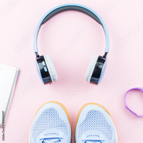 Woman sneakers, headphones, fitness tracker and smartphone on pastel pink background. Sport fashion concept. Flat lay