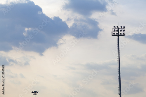 Sports light pole or Stadium Light tower in sport arena on blue sky with clouds. photo