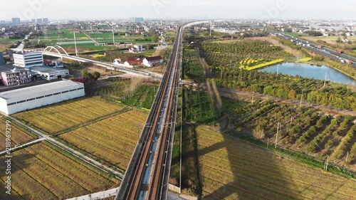 Aerial of Chinese countryside and high speed train. China's bullet train CSR zooming through the rural countryside. Drone shot of moving gaotie on elevated railway.