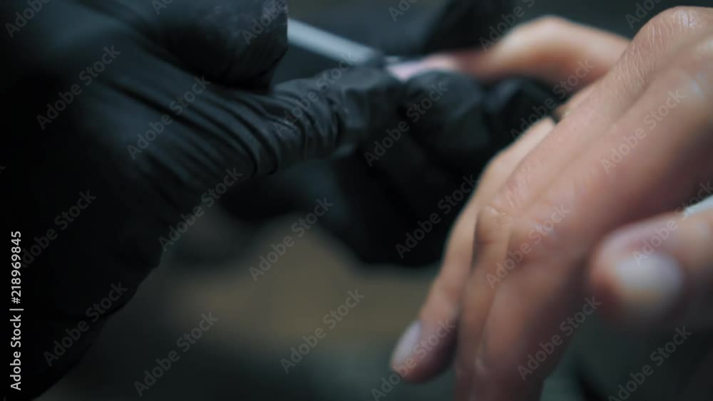 Manicurist is applying professional nail polish to client's nails. Woman is getting nail manicure and spa treatments. Close up Manicurist is applying professional nail polish to client's nails. Woman is getting nail manicure and spa treatments. Close up