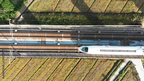 Looking down at Chinese high speed train tracks on raised platform. China's bullet train CSR zooming through the rural countryside. Drone shot of moving gaotie on elevated railway.
