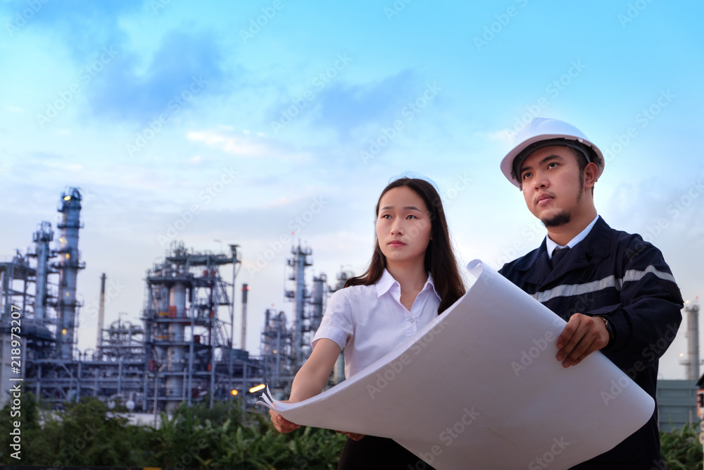 The engineers are checking a layout with large industry background.