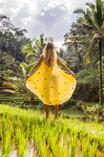 Beautiful young woman in shine through dress. Girl travel and explore world. Typical Asian hillside with rice farming, mountain shape green cascade rice field terraces paddies. Ubud, Bali, Indonesia.