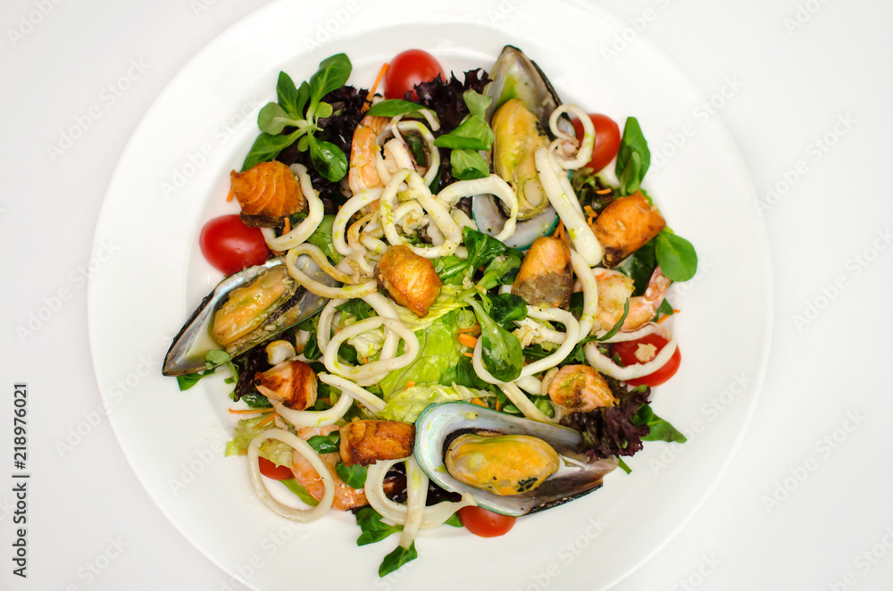 delicious seafood salad. squid rings, mussels, shrimps with fresh vegetables on a white plate. the menu of sea restaurant. delicious seafood salad. squid rings, mussels, shrimps with fresh vegetables on a white plate. the menu of sea restaurant.