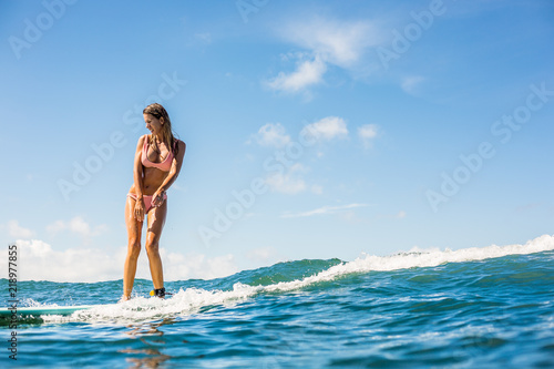 Fitness surfer girl in sexy bikini on surfing longboard ride and have fun on big waves in open ocean. Modern active lifestyle  people water sport adventure camp and extreme swim on summer vacation.