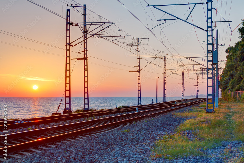 Beautiful landscape of a railroad and towers of traction line on the background of the sea at sunset, Sochi, Russia
