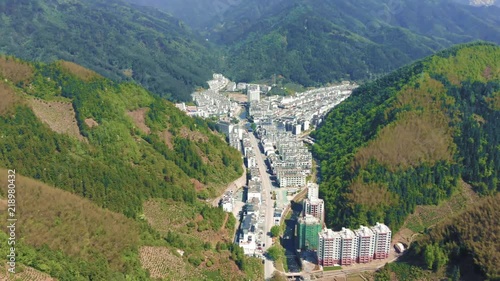 Drone aerial shot of mountain valley city Huangshan city in Tunxi, Anhui. Huangshan mountain tourist attraction, with quaint modern village between giant mountains during very hot summer in China. photo