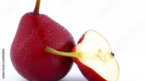 Macro shooting of one whole and one half cut red d'anjou pears with water drops. Rotating on the turntable isolated on the white background. Close-up. Macro. photo