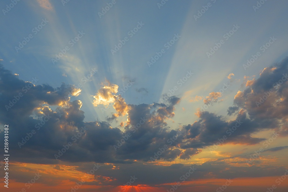 Sun rays shining through dark clouds at sunset, natural background Sun rays shining through dark clouds at sunset, natural background